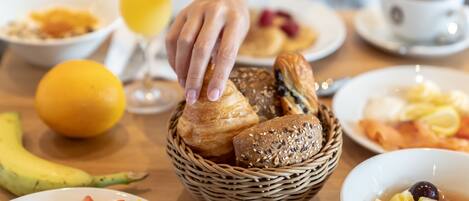A breakfast setting with various foods and a basket of bread.