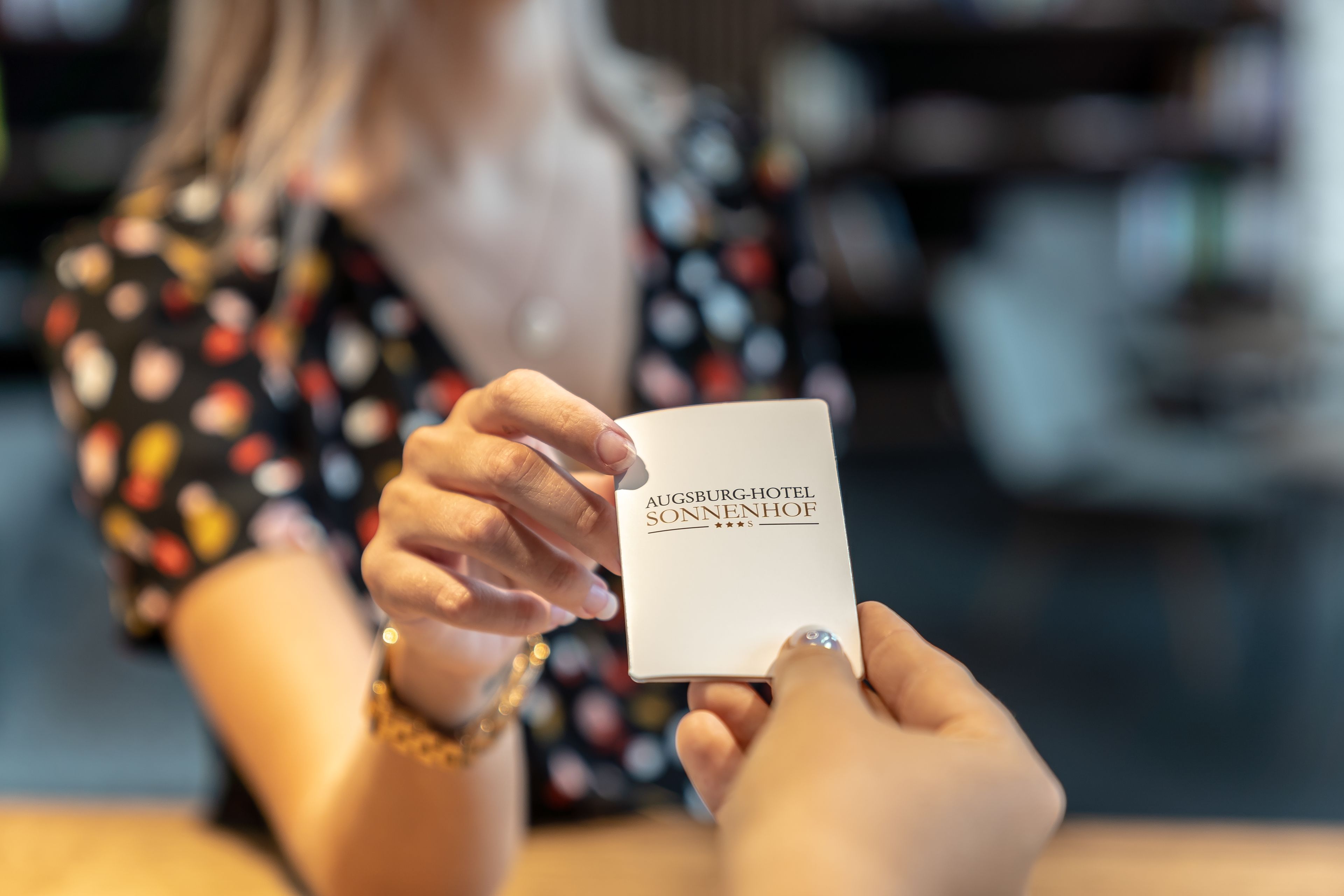 A person holding a card with "Augsburg-Hotel Sonnenhof" written on it.