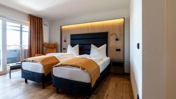 A modern hotel room with a large bed, two bedside tables, a nightstand, and a view of the outdoors.