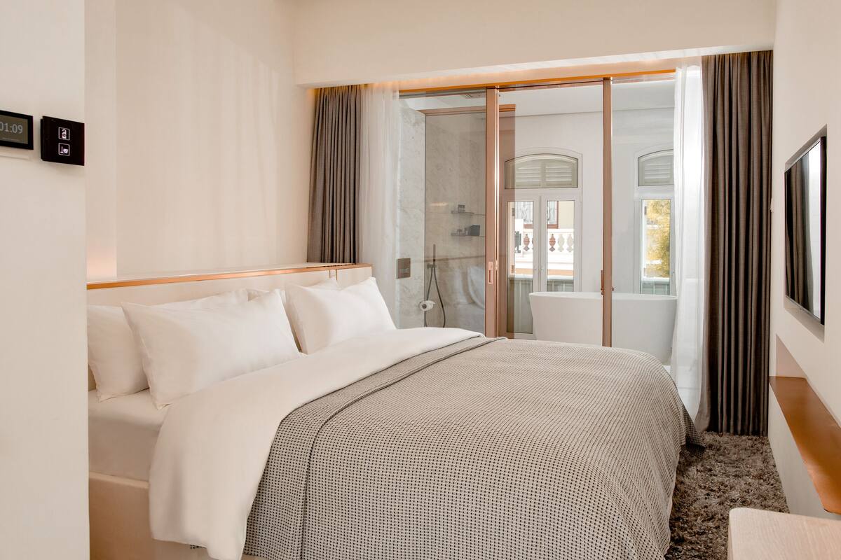 A hotel room with a bed, a shower, and a view of the outside.