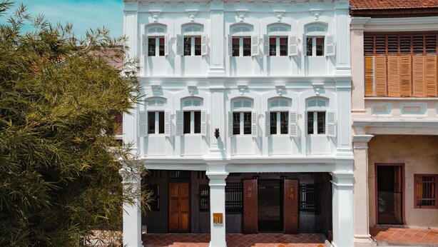 Ein weißes Gebäude im Kolonialstil mit zahlreichen Fenstern und Türen, das traditionelle architektonische Elemente aufweist.