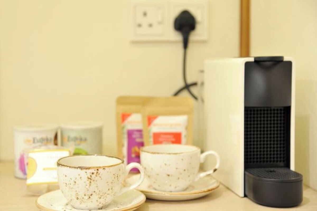 A coffee machine, two cups, and a box of coffee pods on a table.