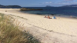 A sandy beach with a wooden walkway leading to the water. - Pensión O Noso (Porto do Son)