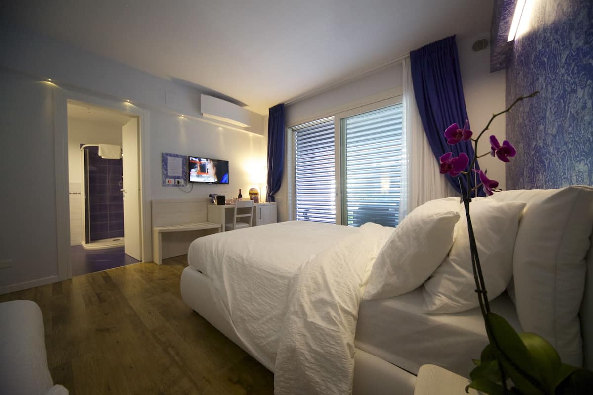 Ein modernes Schlafzimmer mit einem großen Bett, einem Schreibtisch und einem Fernseher.