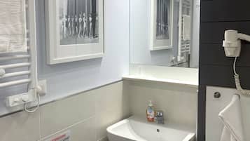 Un baño moderno con un lavamanos blanco, un espejo y un toallero.