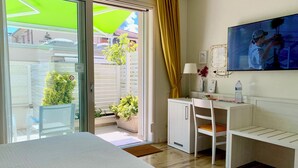 Een hotelkamer met een bed, een bureau met stoel, een televisie en een raam met gordijnen.