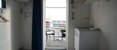 Een kleine, schone kamer met twee bedden, een wastafel en uitzicht op de haven.