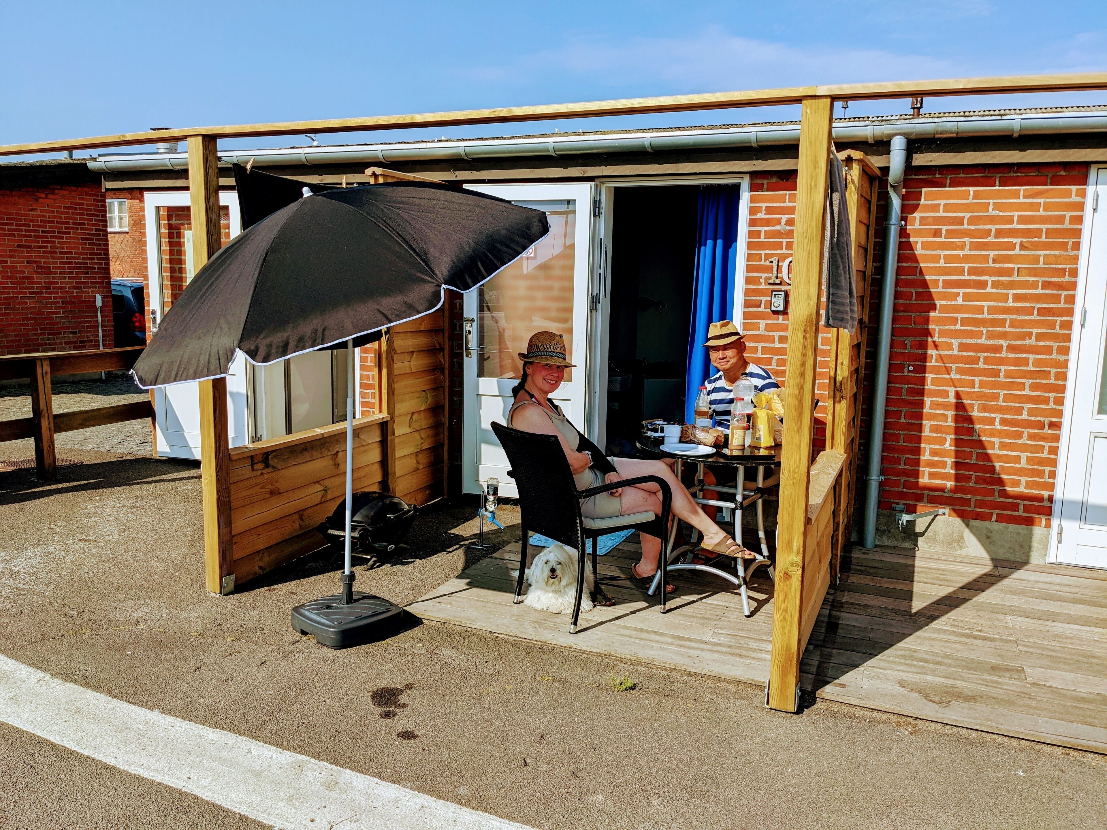 A patio area with a wooden deck, a black umbrella, and a barbecue grill.