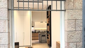 Een compacte, moderne kamer met kitchenette, een eethoek met twee stoelen en een klein zithoekje.