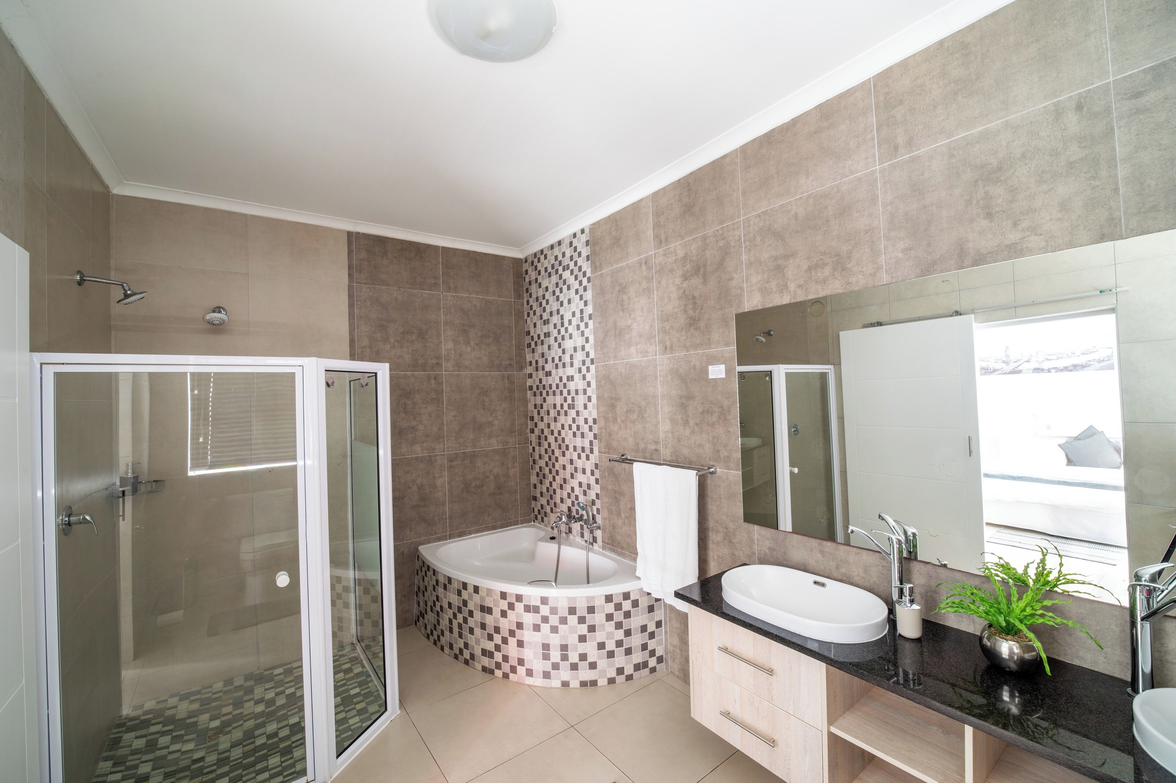 A modern bathroom with a glass-enclosed shower, a freestanding bathtub, a vanity with a sink, and a large mirror.
