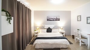 A bedroom with a bed, bedside tables, a desk, and a chair. - Bella Luna B&B (Walvis Bay)