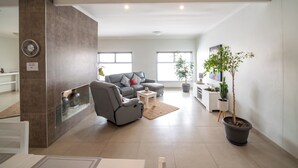 A modern living room with a gray sofa, a glass fireplace, and a potted plant. - Bella Luna B&B (Walvis Bay)