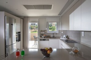Een moderne keuken met roestvrijstalen apparatuur, een fruitschaal op het aanrecht en uitzicht op de omgeving.