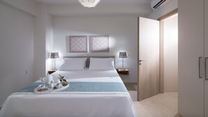 A modern hotel room with a neatly made bed, bedside lamps, a decorative ceiling light, and a small table with a tray of breakfast items. - Gras Houses Agia Pelagia (Malevizi)