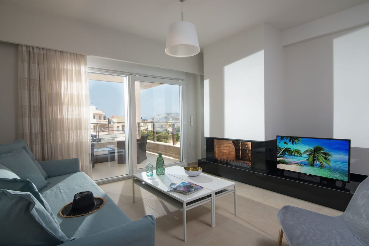 Ein modernes Wohnzimmer mit Sofa, Couchtisch, Fernseher und Kamin.