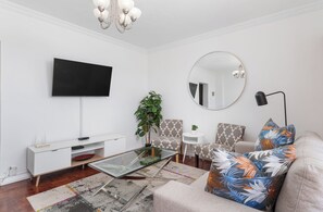 Un salon moderne doté d’un téléviseur à écran plat, d’un miroir rond, d’une table basse en verre et de meubles à motifs.