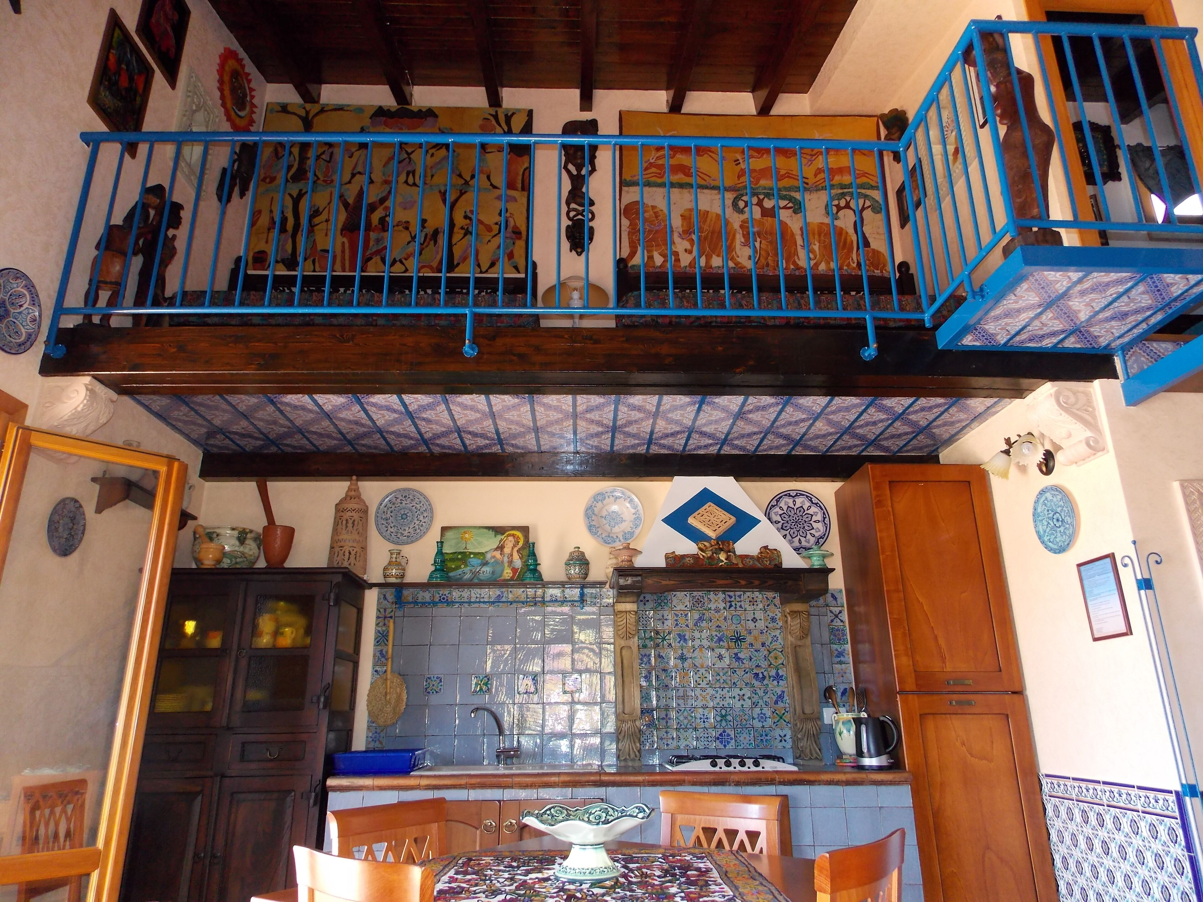 A kitchen with a blue railing, tiled backsplash, and various decorative plates.