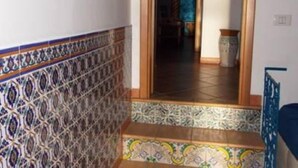 A hallway with patterned tiles and a staircase leading to a room.