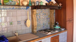 A kitchen with a tiled backsplash, a gas stove, and various decorative items on the shelves.