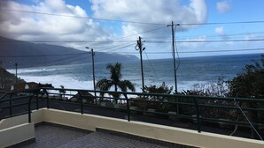 A coastal view from a balcony with a railing, overlooking the sea and distant mountains. - HOUSE CARVOEIRO, SEA AND MOUNTAIN VIEW! (São Vicente, Madeira)