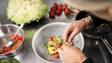 A person preparing a dish with vegetables and a bowl of shredded cabbage.
