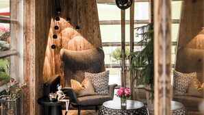 A modern living room with a wooden accent wall, a round coffee table with a vase, and a black floor lamp. - Alpine Boutique Villa Gabriela (Castelrotto)
