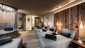 A modern living room with a fireplace, multiple sofas, and a wooden accent wall. - Alpine Boutique Villa Gabriela (Castelrotto)