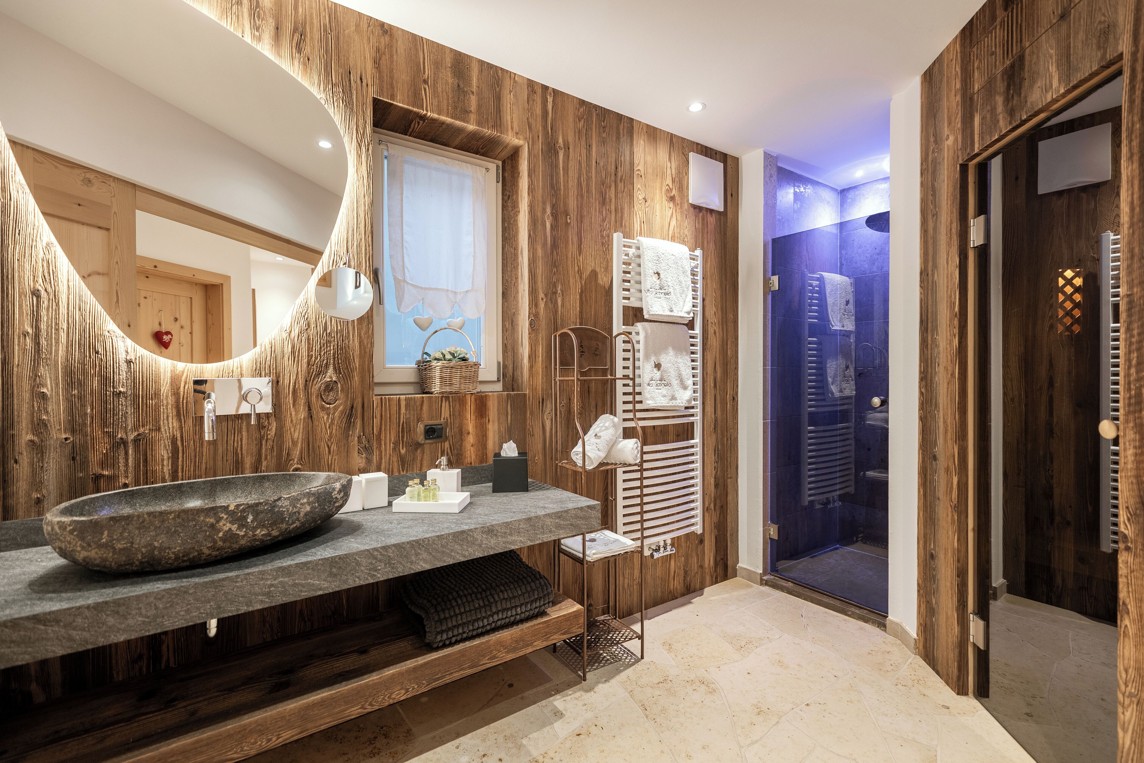 Un baño moderno con una pared de madera, un lavabo ovalado grande y un box de ducha de vidrio.
