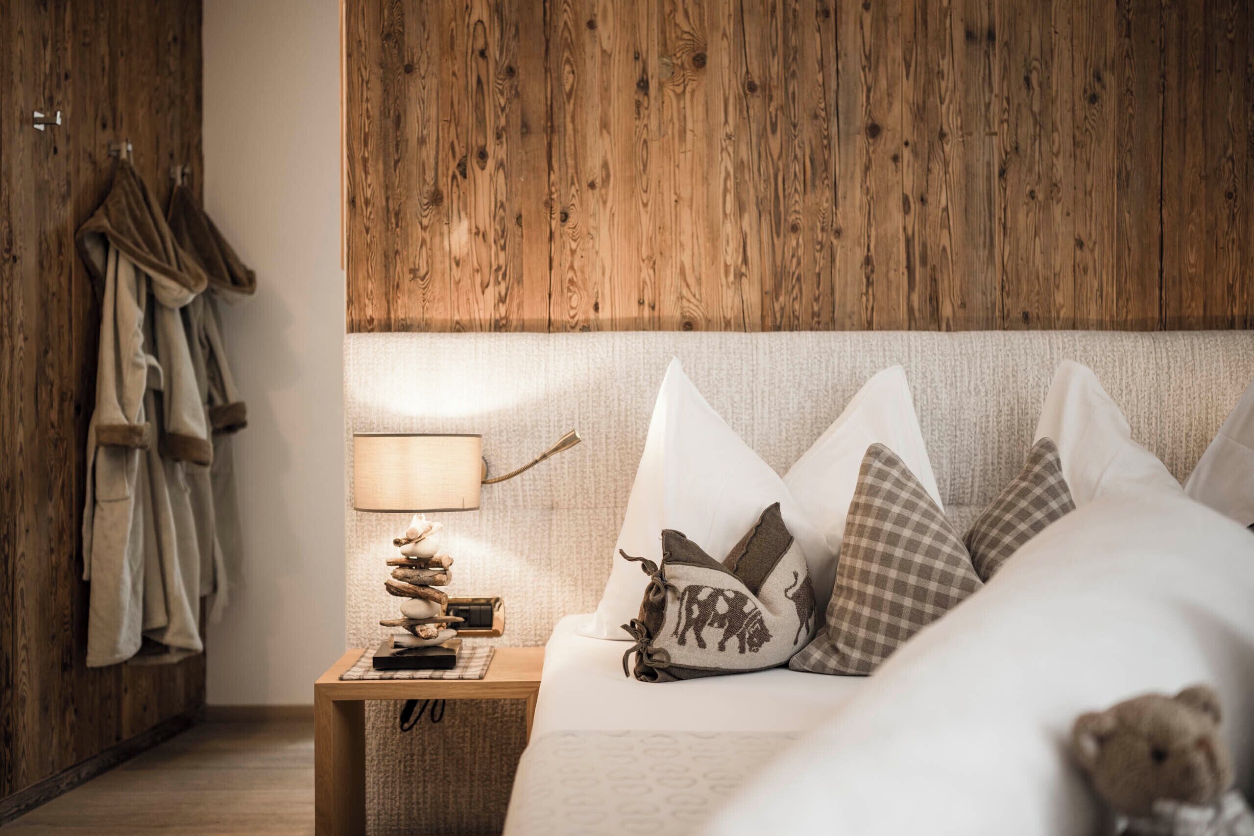 A neatly arranged bedroom with a wooden headboard, a bedside table with a lamp, and a bed with pillows.