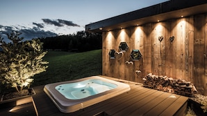 A hot tub on a wooden deck with a wooden wall featuring hexagonal cutouts and heart-shaped decorations. - Alpine Boutique Villa Gabriela (Castelrotto)