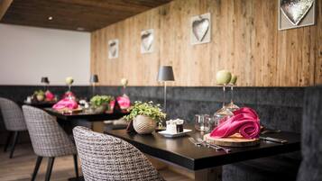 A dining area with a long table set for four, featuring a modern design with a wooden wall and heart-shaped decorations.