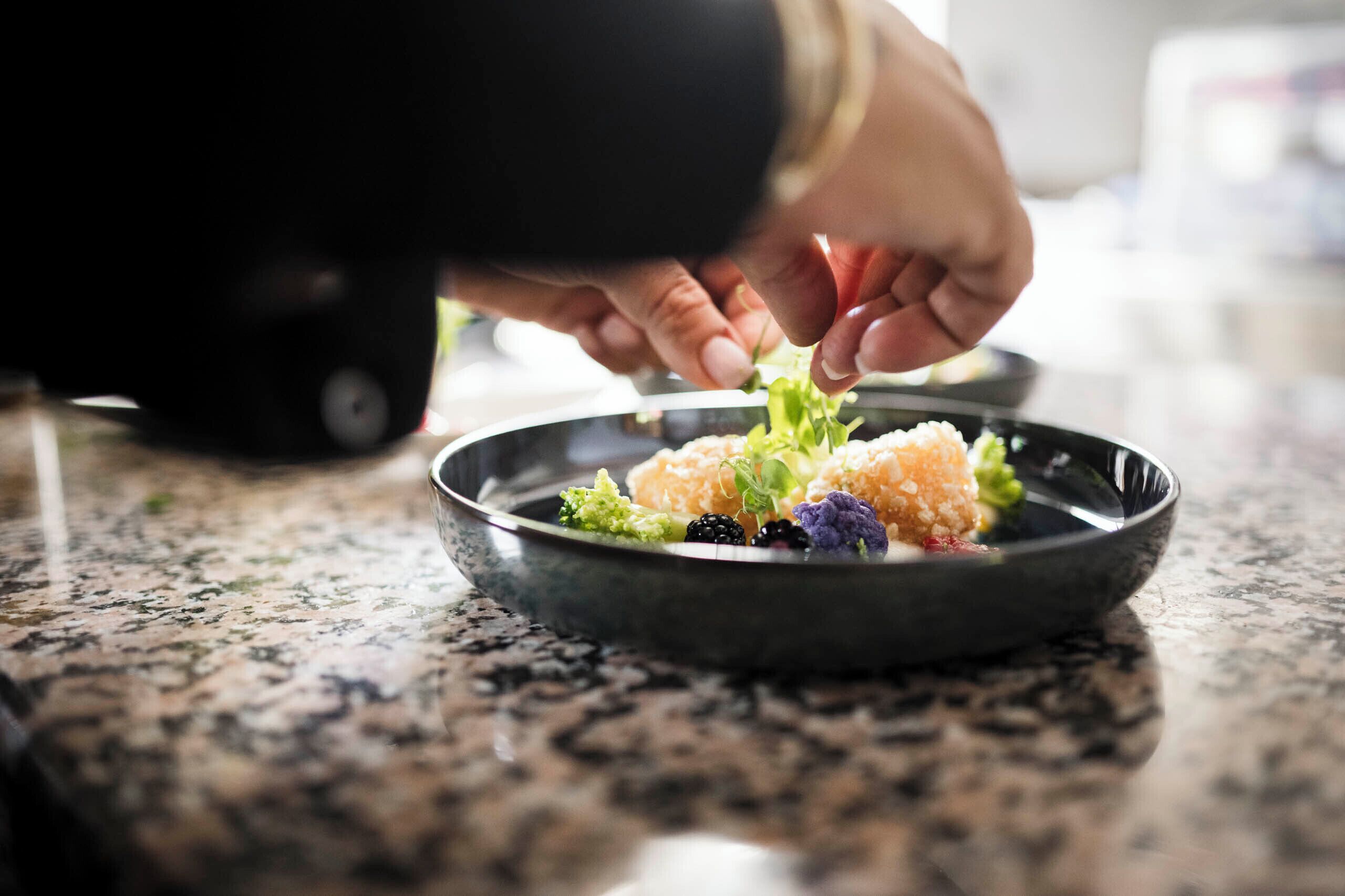 A person placing a dish on a granite countertop.