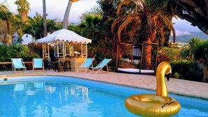 Una piscina con un flotador de cisne, sillas de descanso y una zona de estar cubierta.