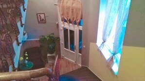 Uma escadaria leva a um quarto com vista para o exterior, uma planta em vaso e uma porta com cortina.