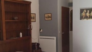 Un dormitorio con cama, armario de madera, una mesita, una silla y un cuadro en la pared.