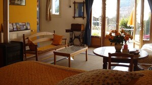 Una habitación acogedora con cama, sofá, mesa y silla. Tiene una ventana con cortinas y vistas al exterior.