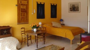 Un dormitorio acogedor con cama, una mesita con un florero, una silla y un armario de madera.