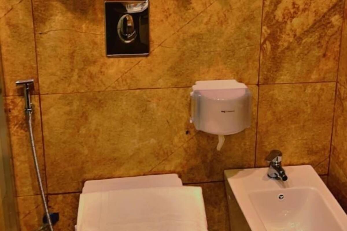 A bathroom with a marble wall, a toilet, a bidet, and a sink.