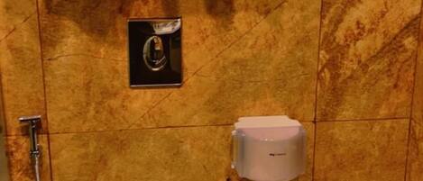 Une salle de bain avec un mur en marbre, des toilettes, un bidet et un lavabo.