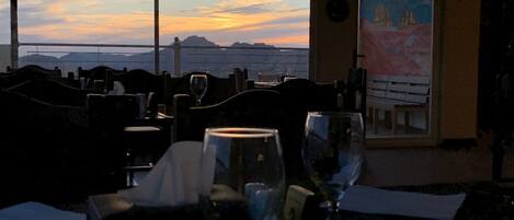 A restaurant with a view of the sunset over the ocean.