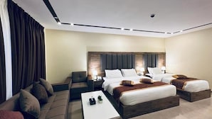 A modern hotel room with a large bed, a sofa, a small table, and a nightstand. - Shaqilath Hotel (Wadi Musa)