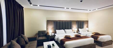 Una camera d'albergo moderna con un letto grande, un divano, un tavolino e un comodino.