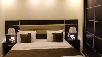 Una habitación de hotel con una cama grande, dos mesitas de noche con lámparas y un cabecero de madera oscura.