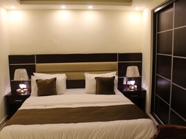 Una habitación de hotel con una cama grande, dos mesitas de noche con lámparas y un cabecero de madera oscura.