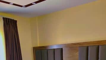 Een hotelkamer met twee bedden, houten hoofdborden en een nachtkastje met een lamp.