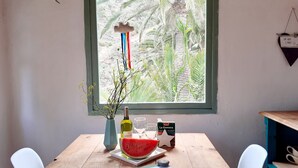 A wooden dining table with a window view of palm trees, a bottle of wine, a watermelon slice, and a star-shaped decoration. - CASA ALMA a dream look that makes you happy (Hermigua) (Hermigua)