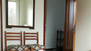 A bedroom with a bed, two wooden chairs, a mirror, and a door leading to another room. - STAY VENICE GUESTHOUSE (Mestre)
