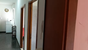A hallway with a refrigerator, a wooden chair, and a door with a telephone. - STAY VENICE GUESTHOUSE (Mestre)
