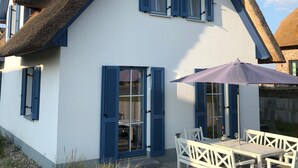 A white house with blue shutters and a thatched roof. - Living under thatch in Seasons - fireplace & sauna  (Groß Schwansee)