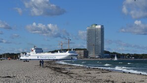 A beach with a ferry named 'Transfennica' and a tall building in the background. - Living under thatch in Seasons - fireplace & sauna  (Groß Schwansee)